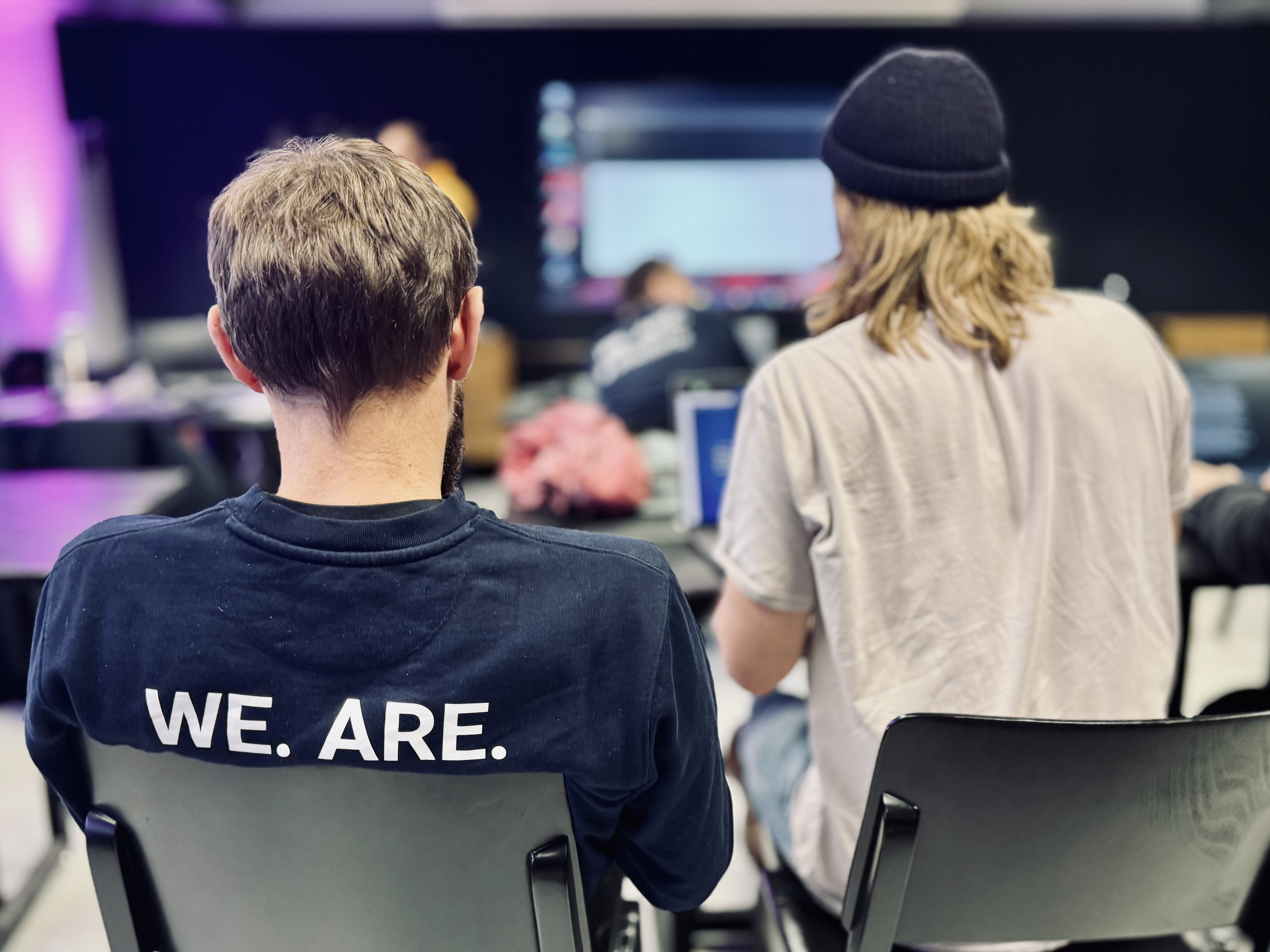 Tobias Mosebach und Arne-Kristian Schulz von hinten fotografiert. Tobias trägt ein dunkelblaues CBlueforte Crewneck; man sieht etwas von dem Schriftzug "WE. ARE. BLUEFORTE".