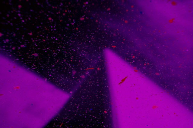 Abstrakte Komposition in Violett- und Magentatönen mit dunklen Flächen, Lichtkegeln und feinen Farbspritzern.